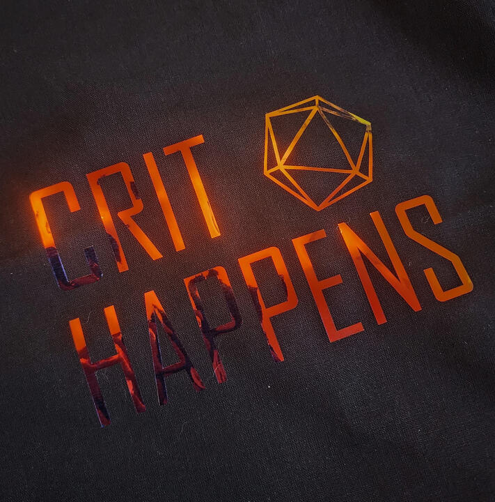Crit Happens Tote Bag A shiny Crit Happens decal on a black tote bag.