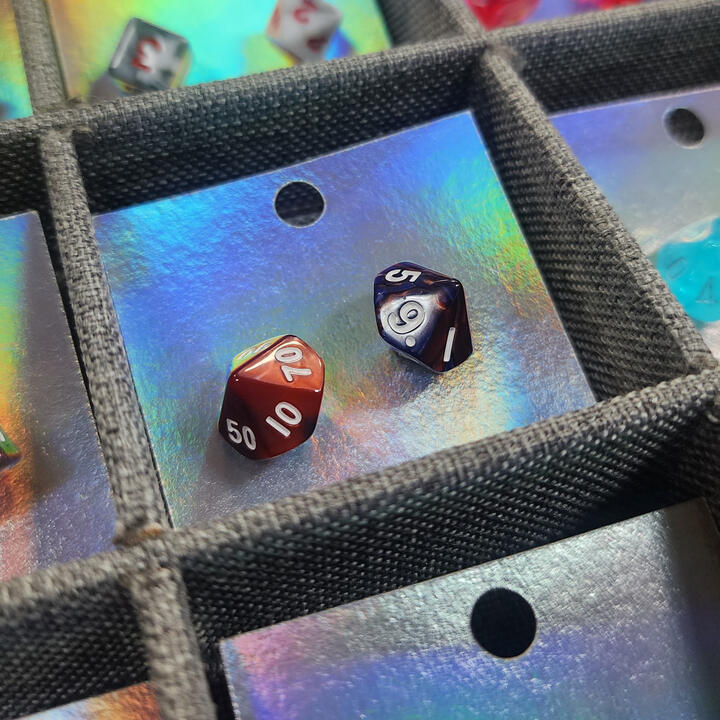 Red and blue d-percentile dice on a holographic card.