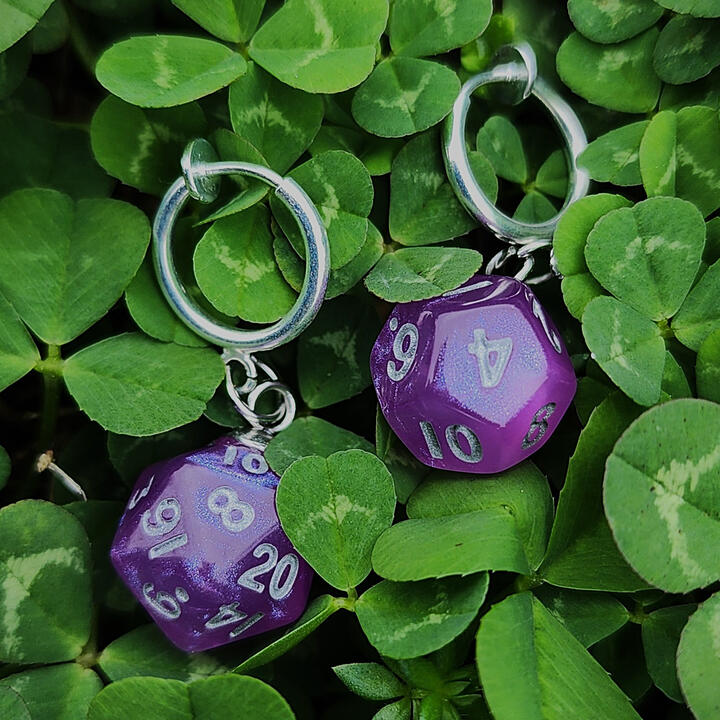 Upcycled Mini Dice Clip-ons A pair of purple mini dice with silver clip-on earrings amongst clovers.